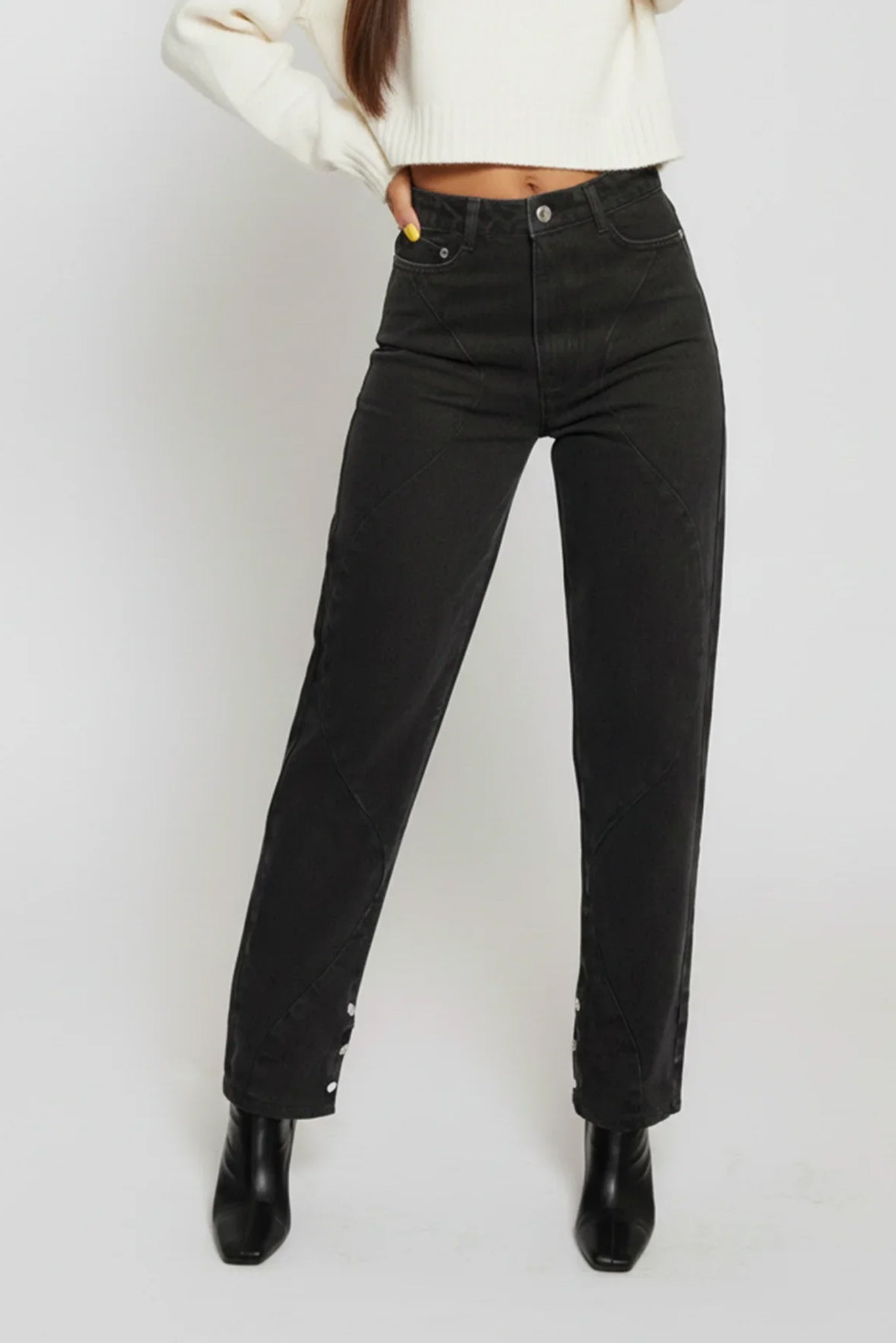 Person wearing black high-waisted jeans on a white background