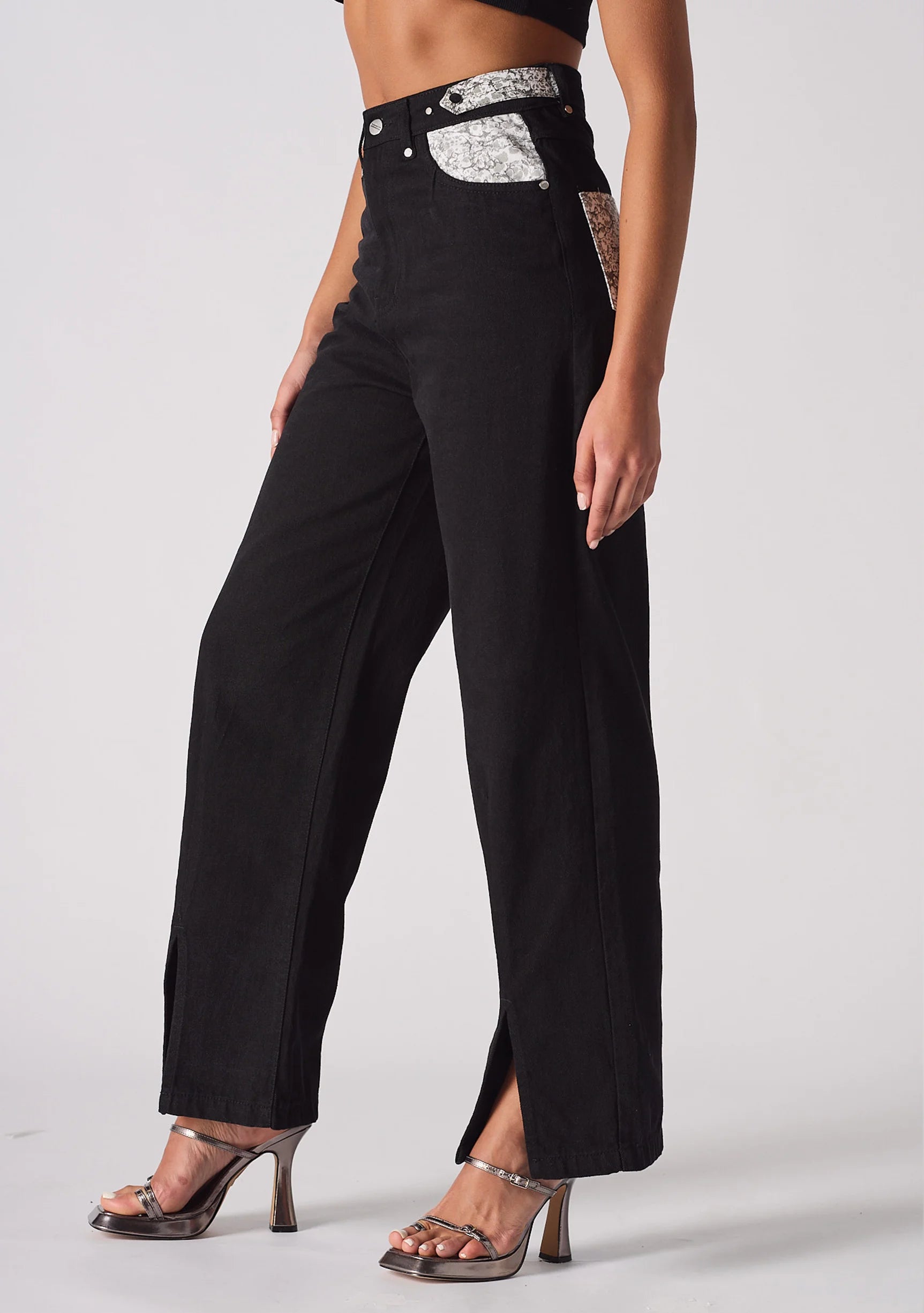 Close up of the button closure and belt loops on black high-waisted jeans