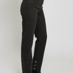 Person wearing black high-waisted jeans with button details on a white background