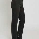 Person wearing black high-waisted jeans with button details on a white background