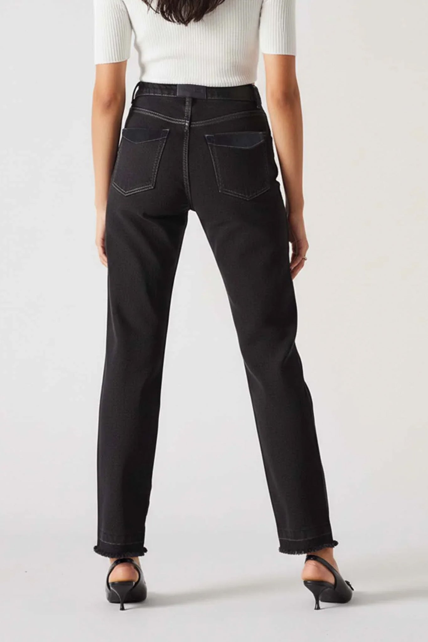Person wearing black jeans and a white top on a plain background