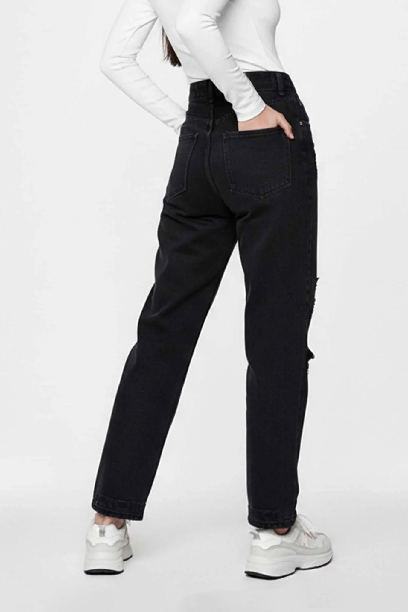 Person wearing black jeans and white sneakers on a white background