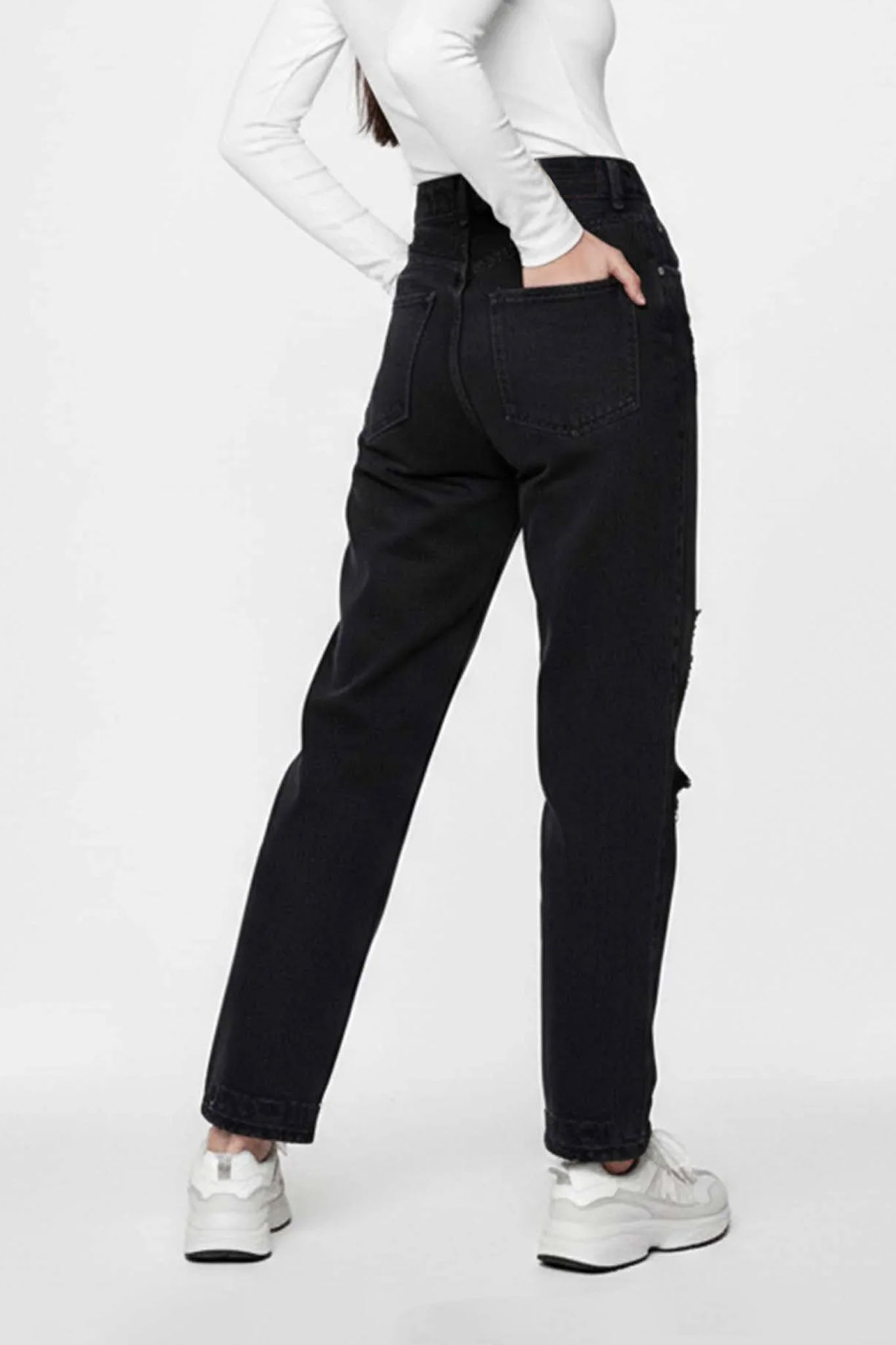 Person wearing black jeans and white sneakers on a white background