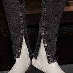 Close-up detail of the silver popper buttons on the ankle of the black jeans