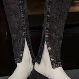 Close-up detail of the silver popper buttons on the ankle of the black jeans