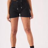 Full length front view of a woman in black jogger shorts and a green cap