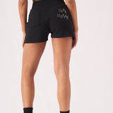 Rear view of a woman wearing black jogger shorts and white trainers