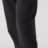 Close-up of the tonal black embroidered logo on the tapered joggers