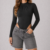 A woman wearing womens-black-mock-neck-bodysuit tucked into grey denim shorts showing the clean fitted finish