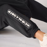 Close up showing the bold linear insignia on the black oversized joggers womens.
