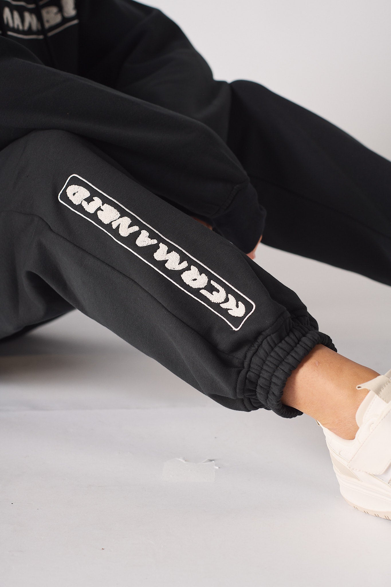 Close up showing the bold linear insignia on the black oversized joggers womens.