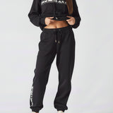 Full body front shot of a model wearing black oversized joggers womens and a sweatshirt.