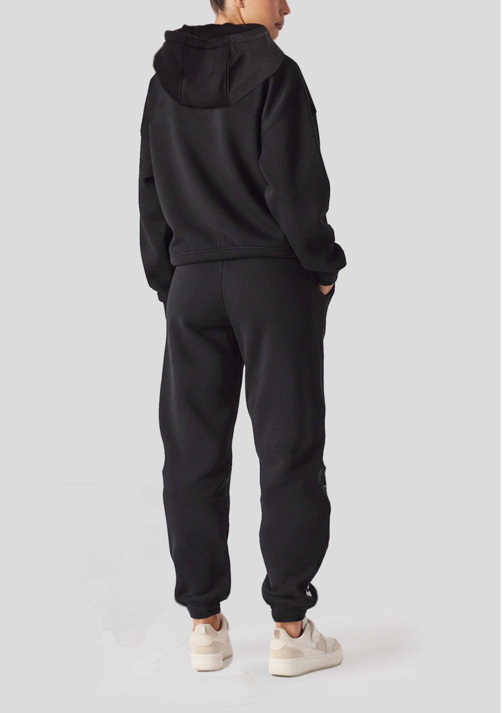 Back view of a model in black oversized joggers womens with a matching hoodie.