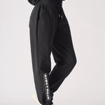 A woman wearing black oversized joggers womens showing side embroidery.