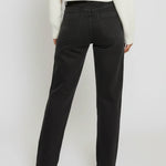 Person wearing black pants and a white top on a plain background