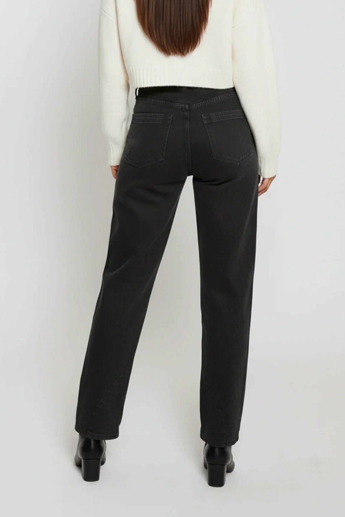 Person wearing black pants and a white top on a plain background