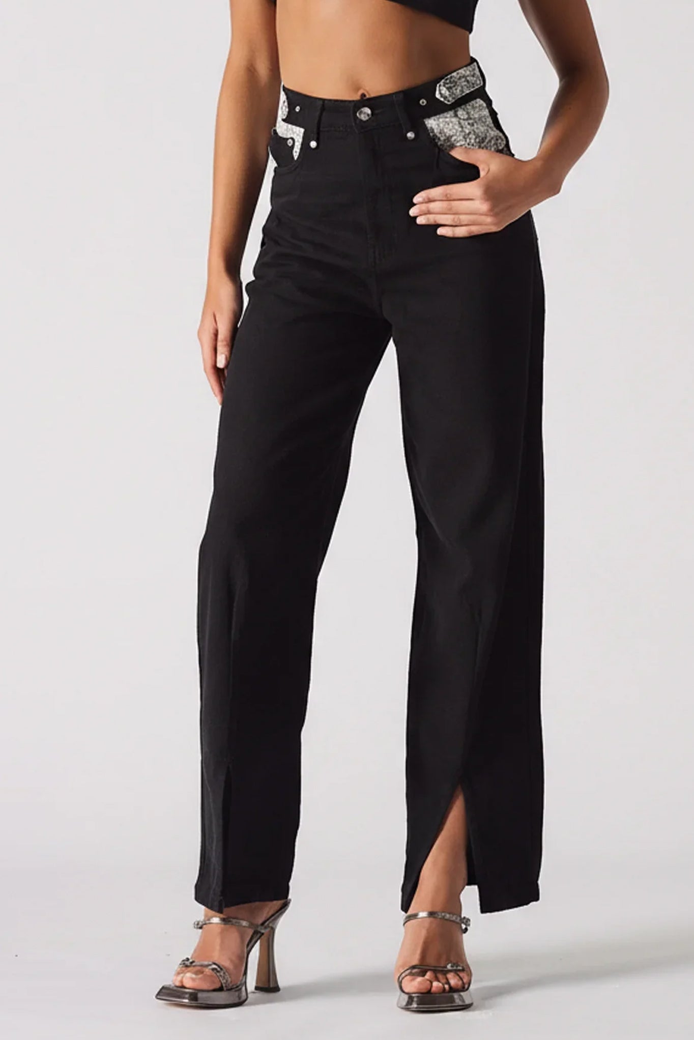 Black pants with a high slit worn by a model on a white background