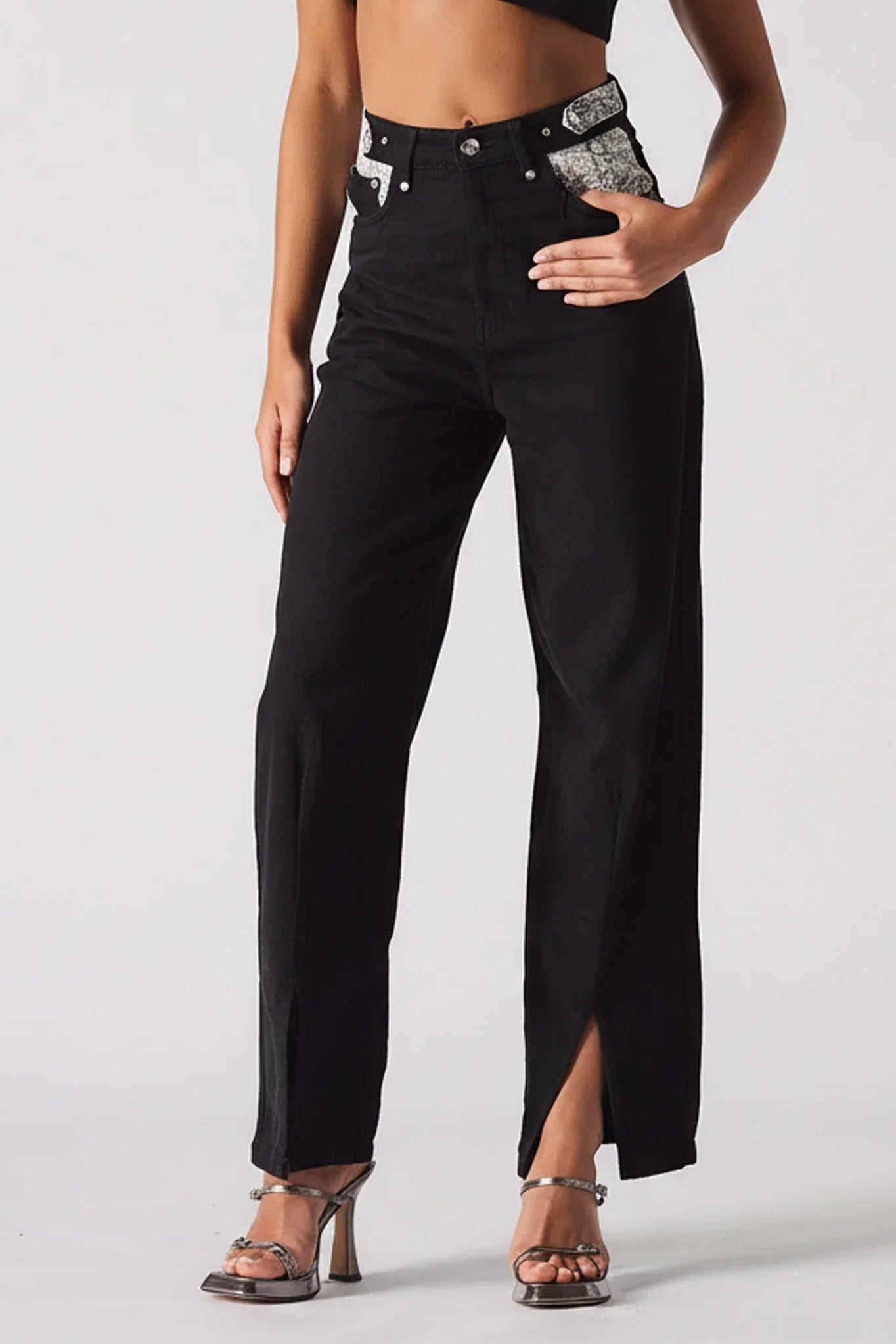 Black pants with a high slit worn by a model on a white background