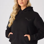 A woman wearing the hood of a soft black pullover hoodie