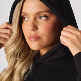 A model posing with arms crossed in a black pullover hoodie
