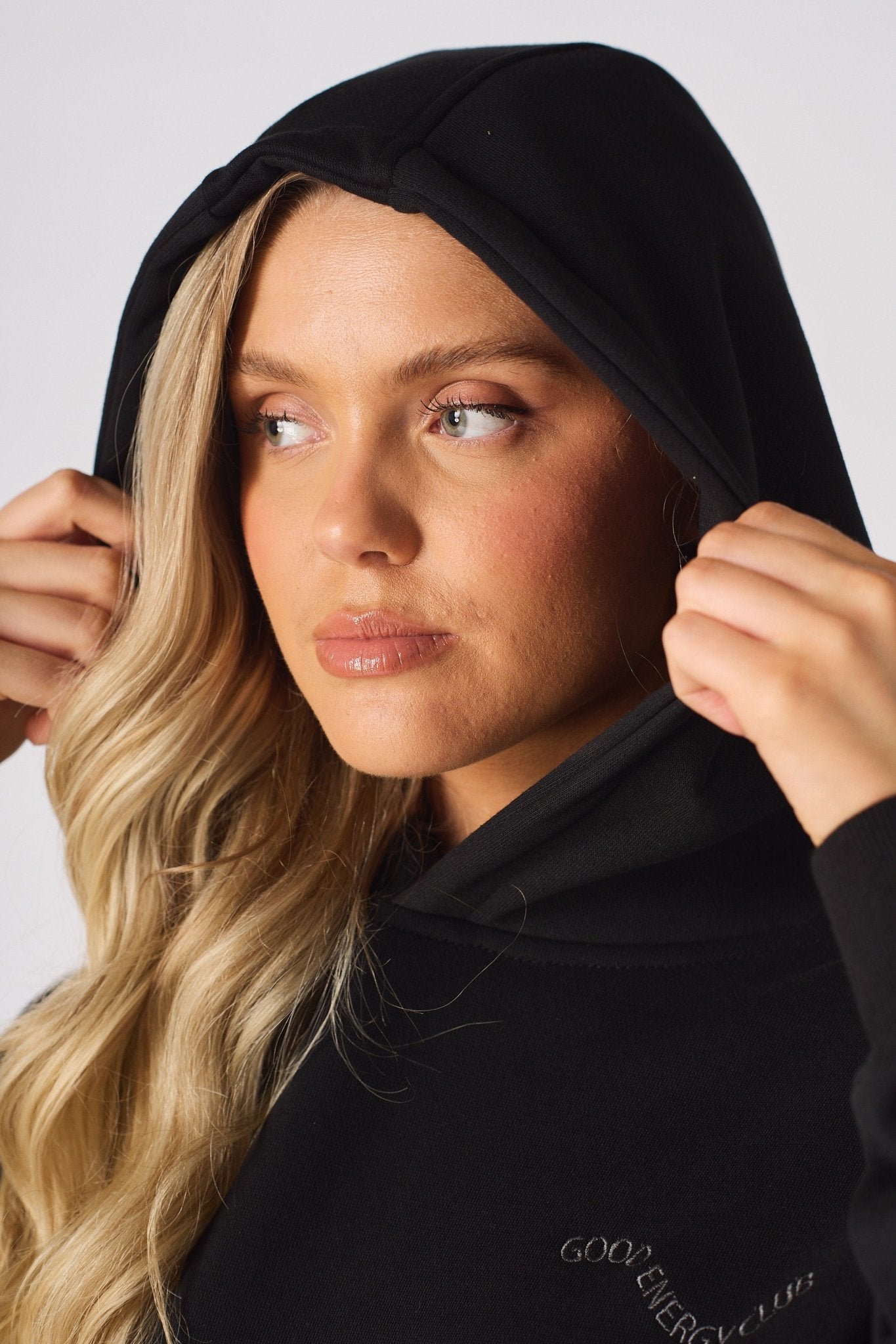 A model posing with arms crossed in a black pullover hoodie