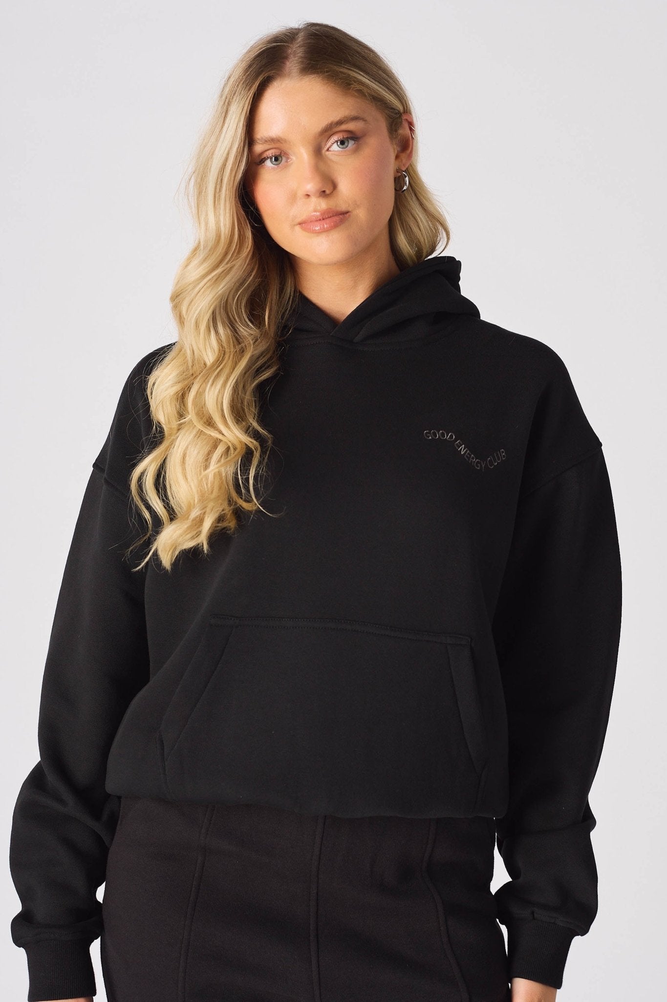 Close up of hands in the kangaroo pocket of a black pullover hoodie