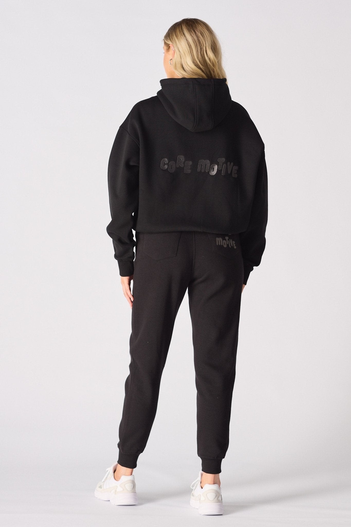 A model wearing a black pullover hoodie with hands on hips
