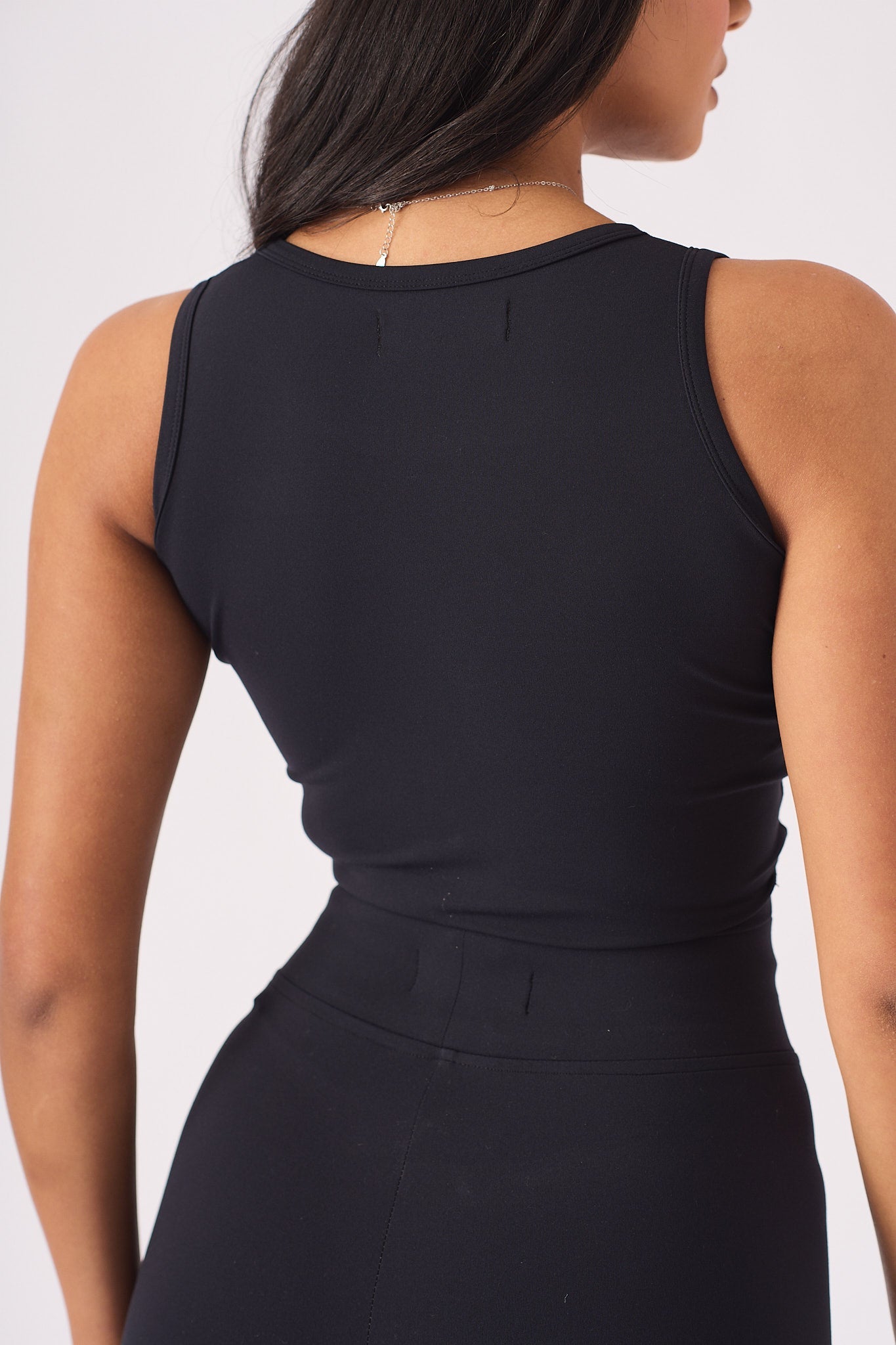 Detailed shot of the back profile and neckline of a black racer neck crop top