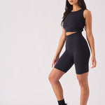 Side profile view of a model styling a black racer neck crop top for gym wear