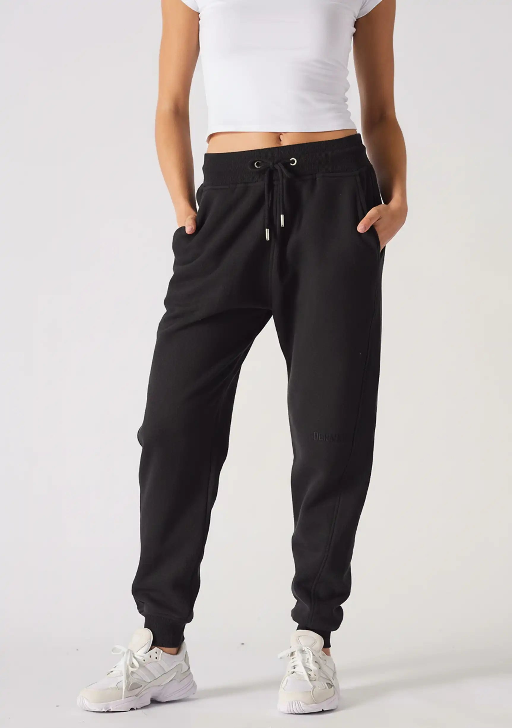 A woman wearing black relaxed fit joggers womens standing against a plain background.