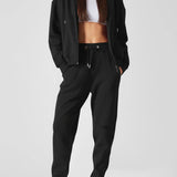 Full body shot of a woman in black relaxed fit joggers womens and a matching jacket.