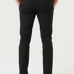 Confident man posing with crossed legs in stylish black slim fit trousers.