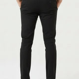 Confident man posing with crossed legs in stylish black slim fit trousers.