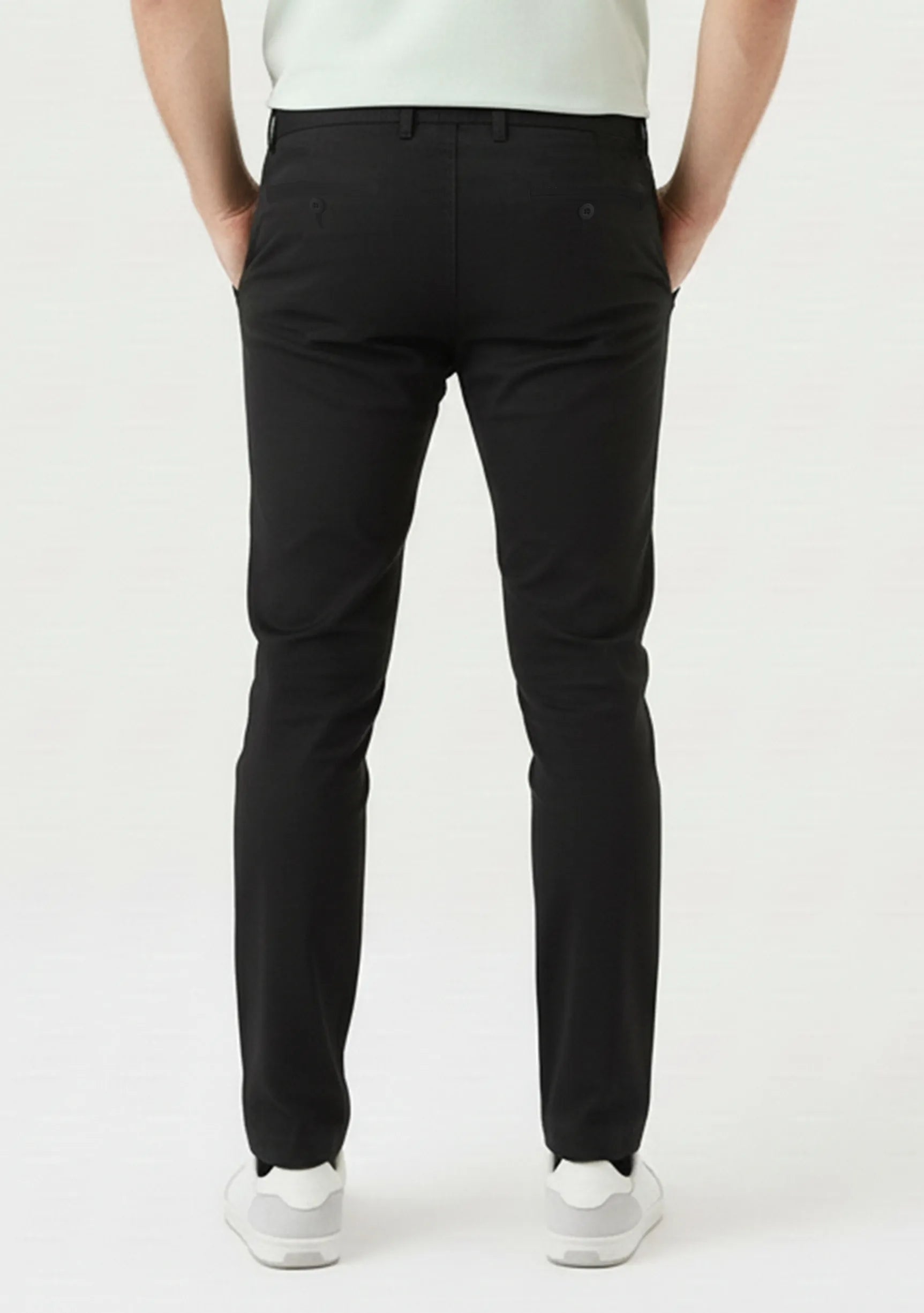 Confident man posing with crossed legs in stylish black slim fit trousers.