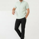 Man leaning against a white prop wearing Jmojo black slim fit trousers.