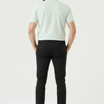 Model sitting on a white block wearing comfortable stretch black slim fit trousers.