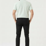 Model sitting on a white block wearing comfortable stretch black slim fit trousers.