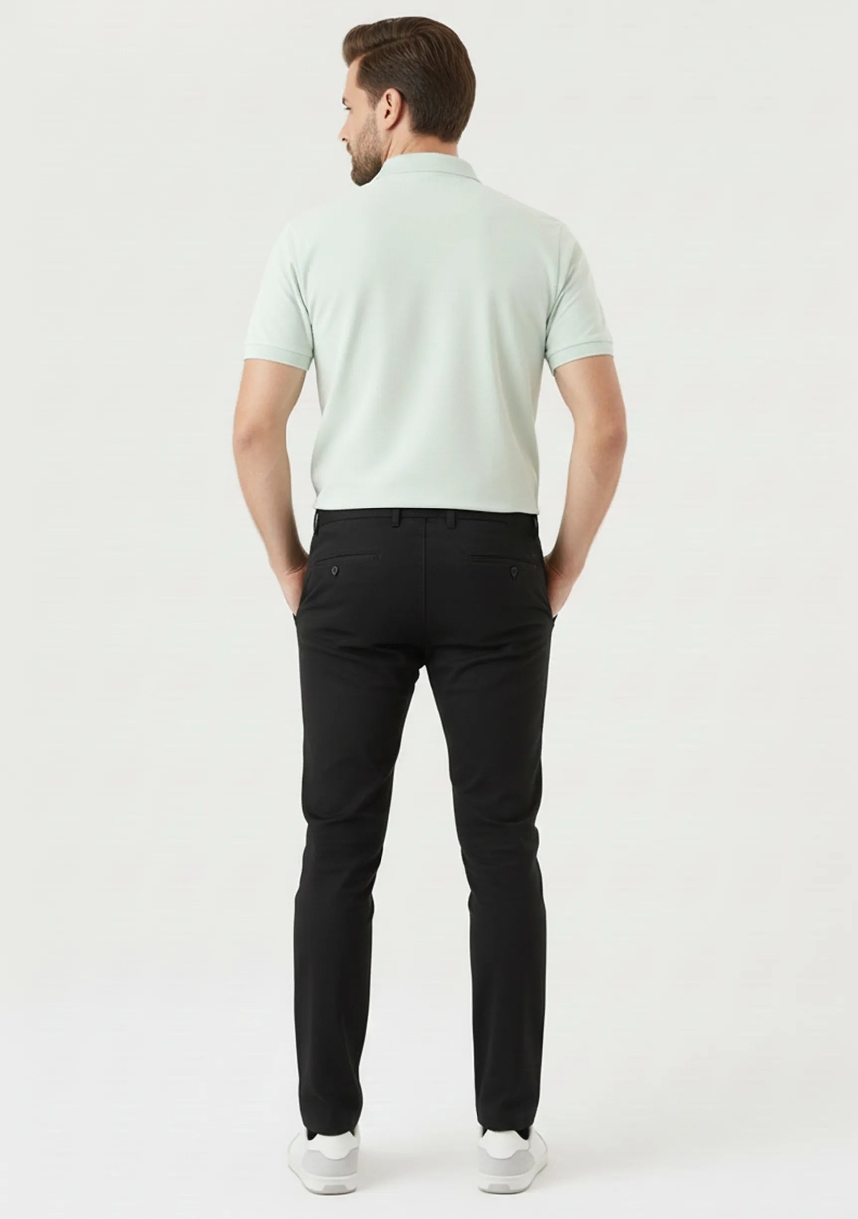 Model sitting on a white block wearing comfortable stretch black slim fit trousers.