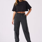 A woman posing in black straight leg cargo pants women's with a matching black crop top.