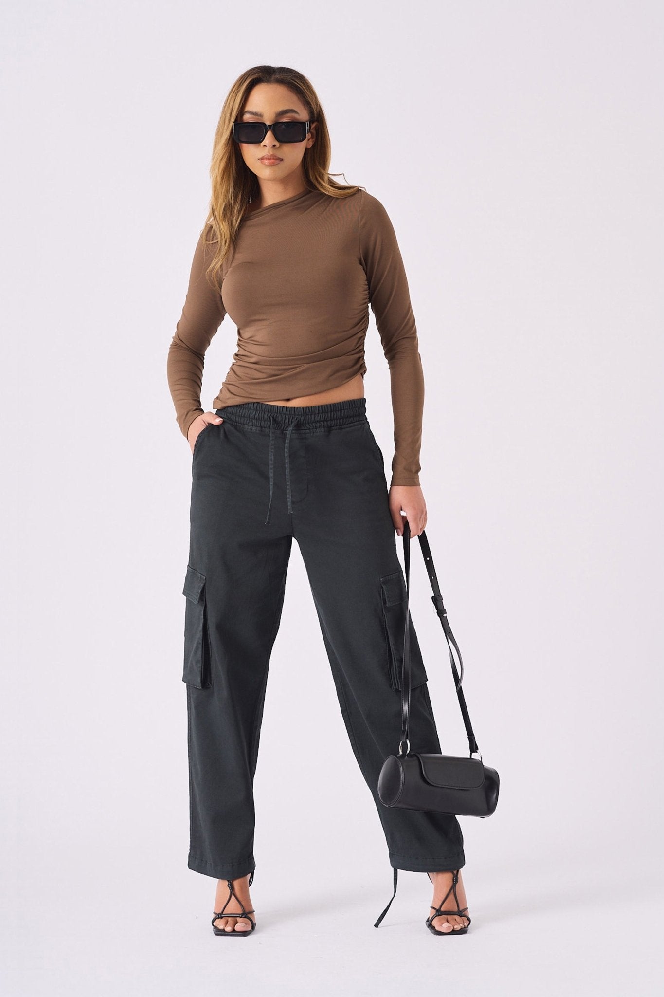 A model wearing black straight leg cargo pants women's and dark sunglasses.