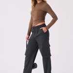 A woman standing in stylish black straight leg cargo pants women's with a brown top