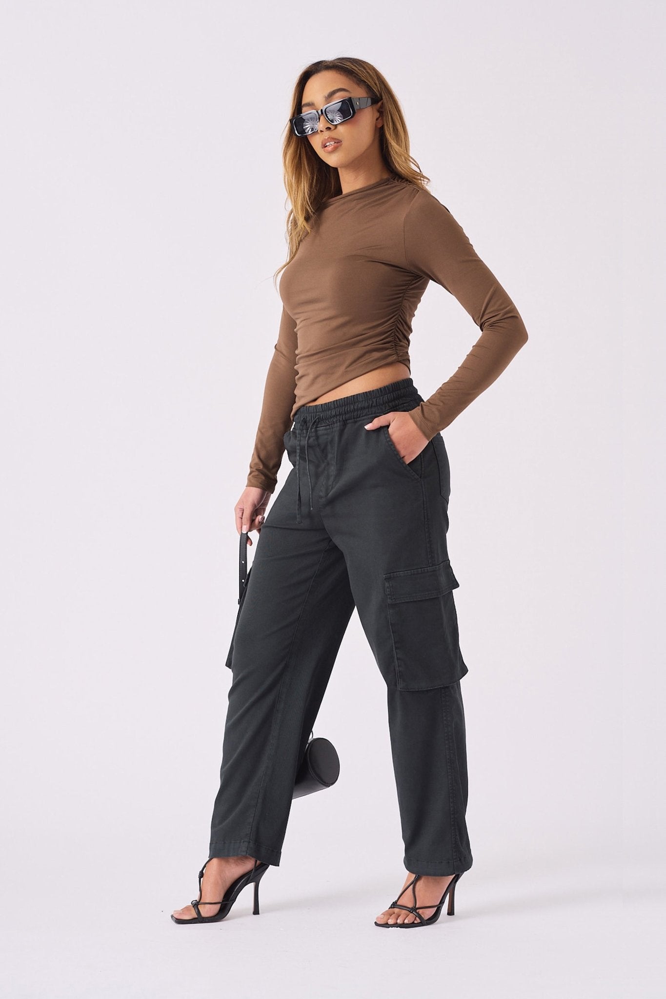 A woman standing in stylish black straight leg cargo pants women's with a brown top