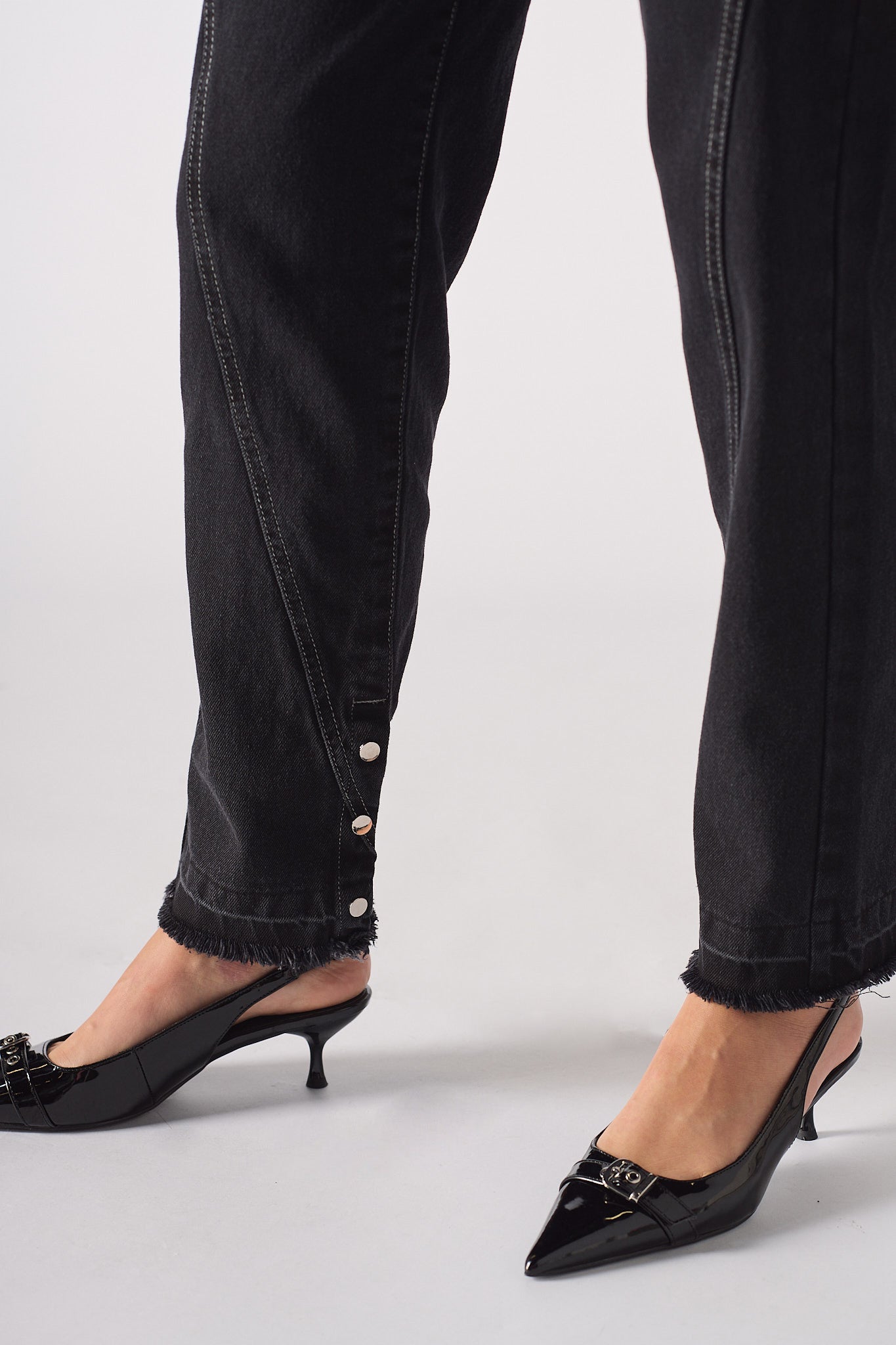 Close-up on the popper ankle detail and frayed hem of Black Wash Straight Leg Jeans