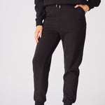 A woman walking comfortably in black tapered joggers womens for a casual look.