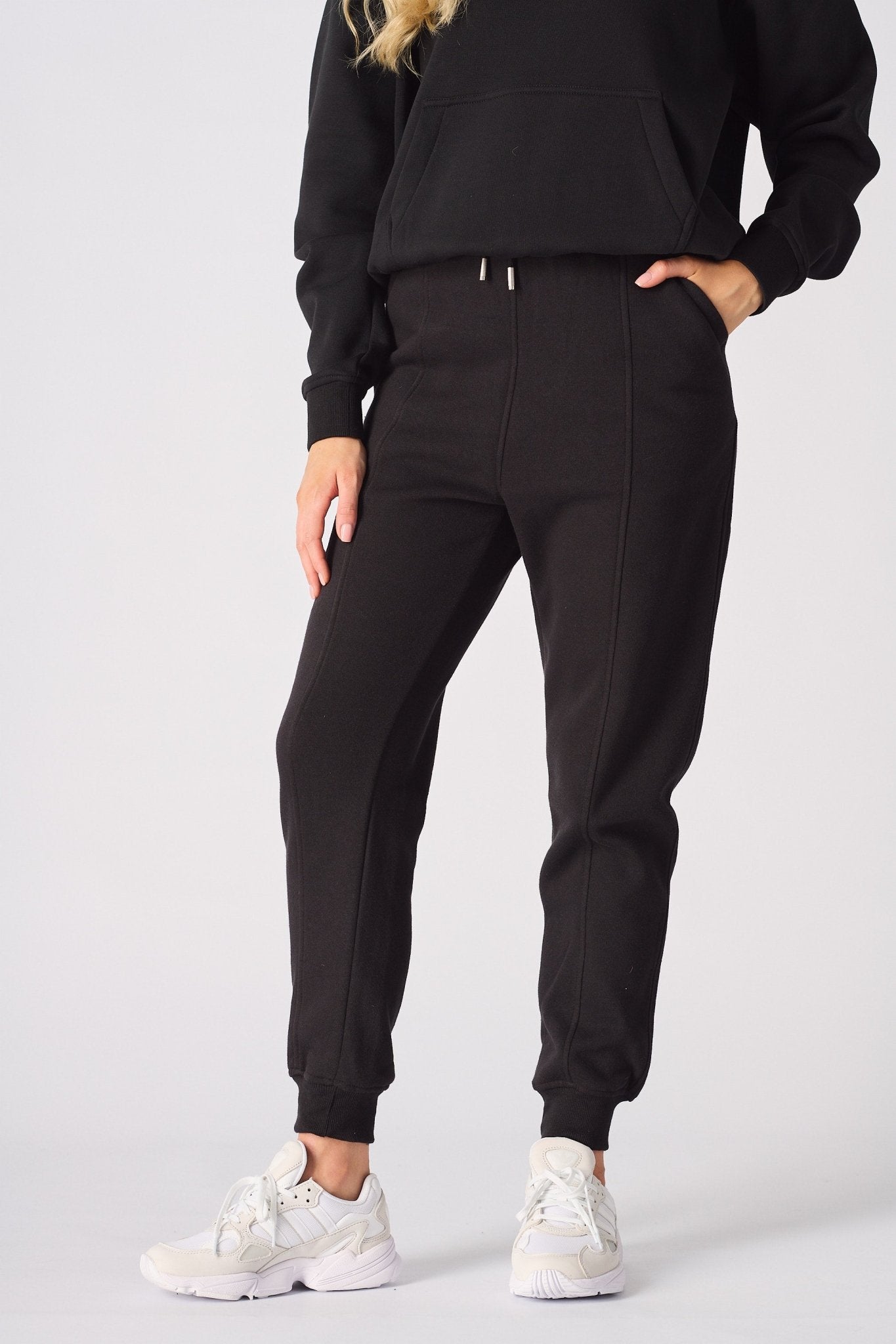 A woman walking comfortably in black tapered joggers womens for a casual look.