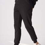 Side angle of a model walking in high quality black tapered joggers womens.