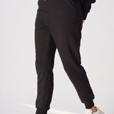 Side angle of a model walking in high quality black tapered joggers womens.