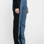 Person wearing black top and blue jeans with a white background
