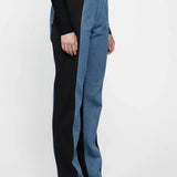 Person wearing black top and blue jeans with a white background