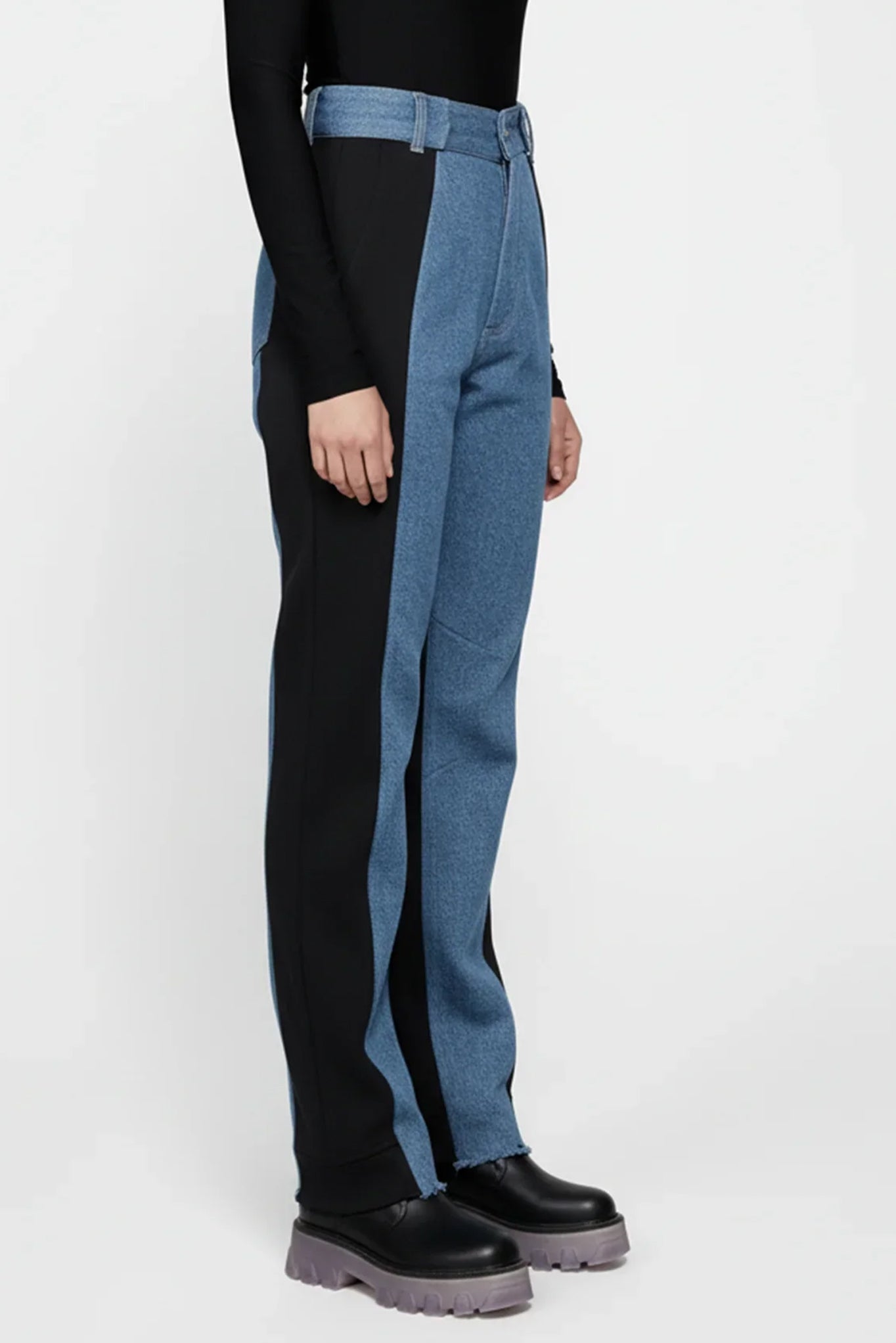 Person wearing black top and blue jeans with a white background
